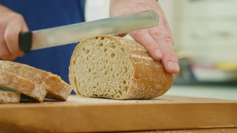 Man Slicing Loaf Of Bread With Knife On Cutting Board Stock Footage 86115137