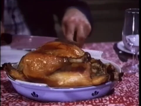 Man slicing roasted chicken at dinner table, 1980s Видео 260257804