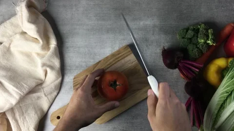 A man slicing a tomato on a chopping board Stock Footage