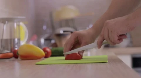 A man is slicing vegetables in the kitchen - tomato and pepper Stock Footage 54218618