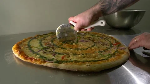 A man slicing up a very large vegetables pizza on a kitchen table 60fps 4K Stock Footage 192458606