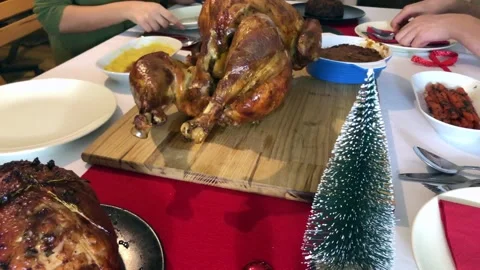 A man slicing whole roast turkey with people around the Christmas dinner table Stock Footage