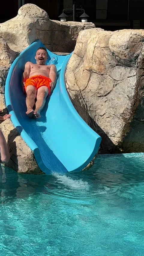 Man sliding down blue curved water slide Stock Footage 345495813