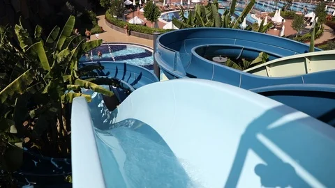Man sliding down fun water slide at sunny day Stock Footage 101262572