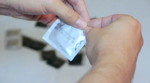 A man slowly opens the package with a condom, close-up 스톡 동영상 66002897