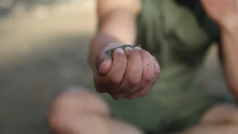 Man slowly pouring sand out of his hand, sea Stock Footage 238761153
