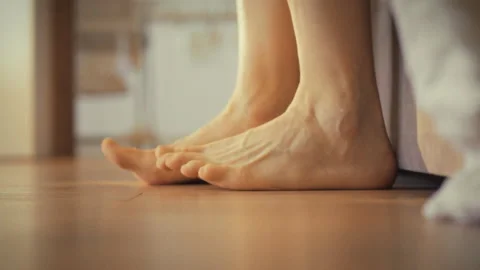 Man slowly rises from bed stretching his legs before taking a step onto the Stock Footage 335124849