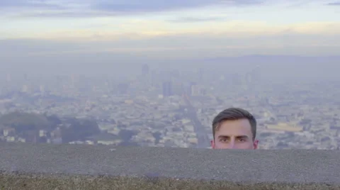 Man Slowly Rises Up From Behind A Wall, With A Straight Face, It's Funny Stock Footage 47688291