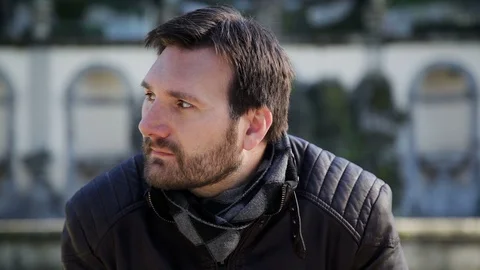 A man with a small beard in a leather jacket looking at the camera and smiling Stock Footage 102280015