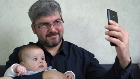 A man with a small child communicates via video link 4K Stock Footage 129529650