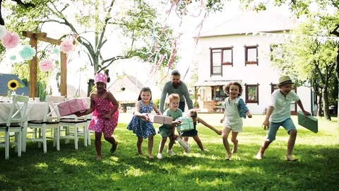 Man with small children with present outdoors in garden on birthday party Stock Footage