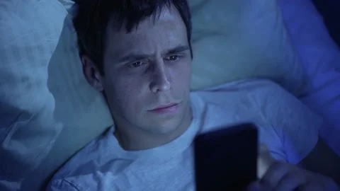 Man with smarthone in a bed at night 스톡 동영상 165348368
