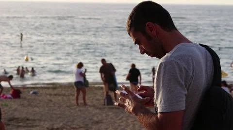 Man with smartphone on the beach at sunset Video stock 55273617