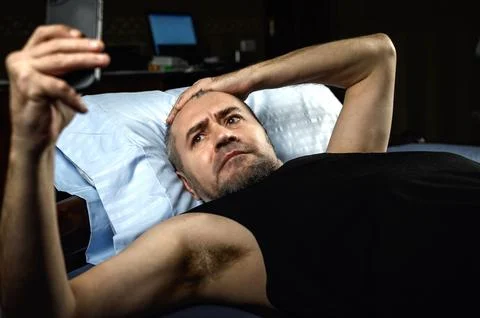 Man with smartphone in bed at night. Handsome man using mobile phone in bed.. Foto stock