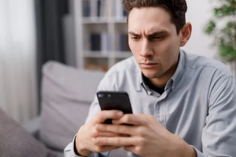Man with smartphone on couch Stock Photos