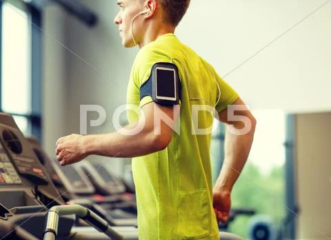 Man with smartphone exercising on treadmill in gym Stock Photos