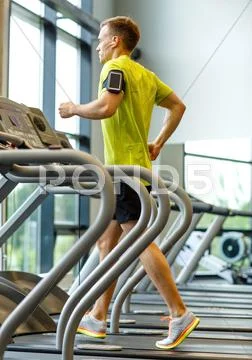 Man with smartphone exercising on treadmill in gym Stock Photos