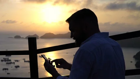 Man with smartphone by Ha Long Bay in Vietnam during sunset Stock Footage 163342670
