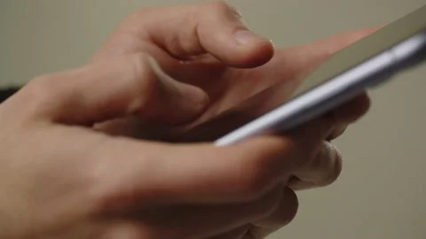 A man with a smartphone in his hands taps on the screen. Person is typing a Stock Footage 236772177