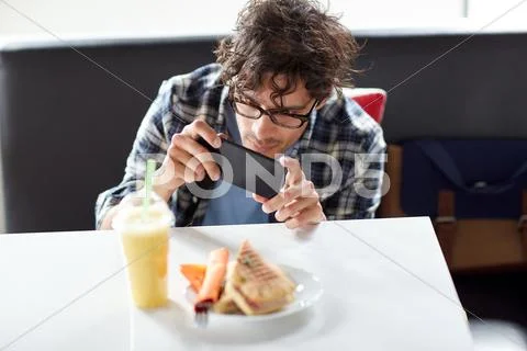 Man with smartphone photographing food at cafe Stock Photos