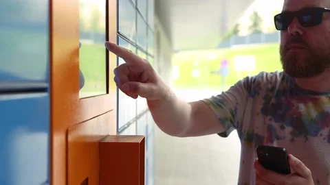 Man with smartphone picks up parcel from automated postal machine. Stock Footage 218146356