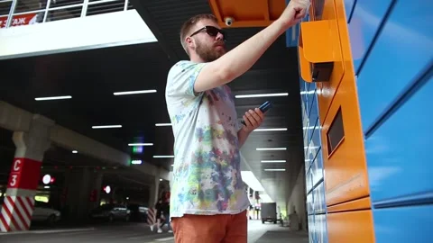 Man with smartphone picks up parcel from automated postal machine. Stock Footage 218146401
