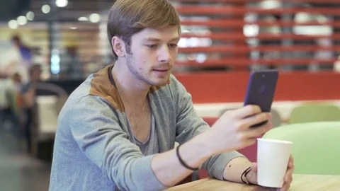 Man with Smartphone in restaurant gets Stressed while Chatting Stock Footage 78813023