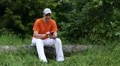Man with smartphone sits on a fallen tree in the forest HD Footage