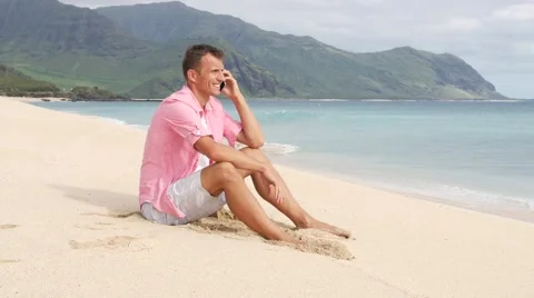 Man with smartphone sitting and talking on the beach Stock Footage 66498872