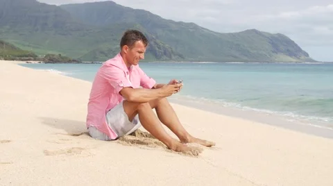 Man with smartphone sitting on the beach Stock Footage 66498929