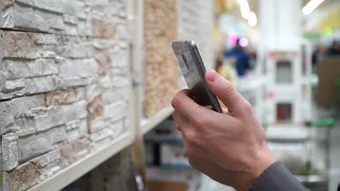 Man with smartphone at store selecting materials for renovation of his house Stock Footage 88128751