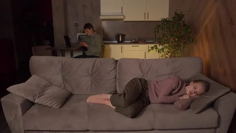 A man with a smartphone is working on a laptop in the kitchen while his wife is Stock Footage 145066726