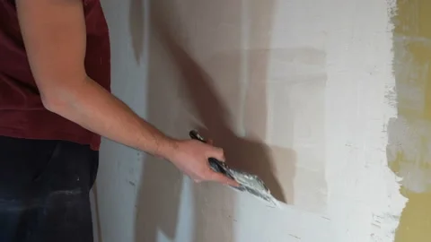 Man smears putty on the wall 4K Video stock 147895069