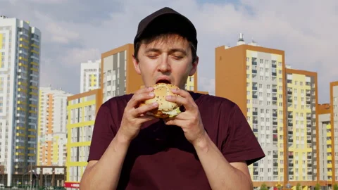 A man is smelling and biting a hamburger with great appetite Video stock 201410587
