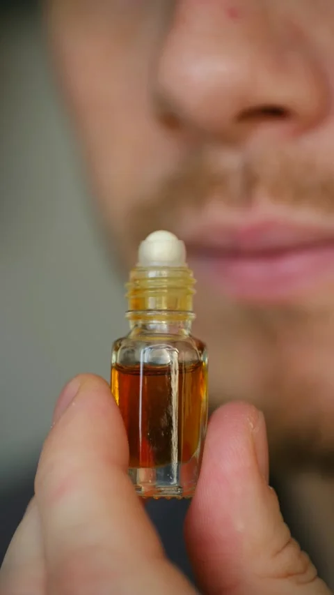 Man smelling perfume oil from a roll on bottle Vidéo 337548083