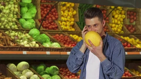 Man smells melon at the supermarket Stock Footage 76680680