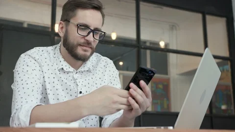 Man smile and using phone for chatting in office Stock Footage 87874448