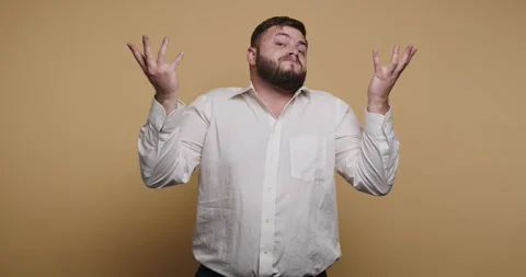 Man smiles while adjusting his shirt in front of a solid background 動画素材 326797766