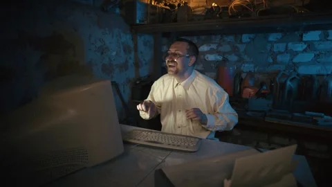 Man smiles while typing on a vintage computer in a dim basement. 스톡 동영상 329511787