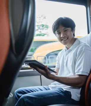 A man smiles while using a tablet while sitting Stock Photos