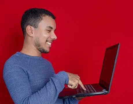 Man smiling and doing a gesture in front of  a laptop Stock Photos