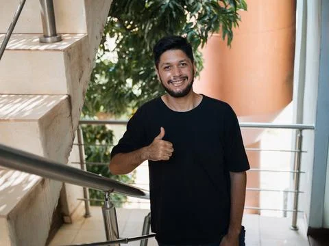 Man smiling and doing thumbs up on stairs landing Stock Photos