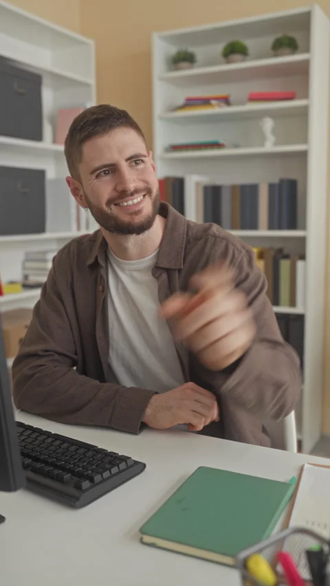 Man smiling and pointing at computer monitor while seated at desk with keyb.. Stock Footage 337362583