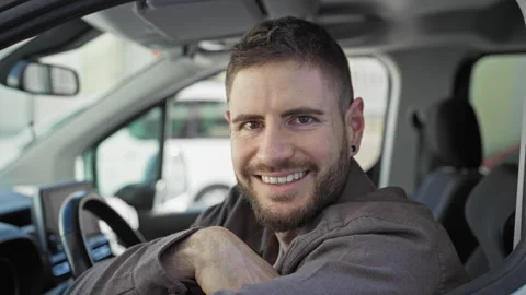 Man smiling with arm resting on car window, hand on steering wheel, beard v.. Vidéo 337366002