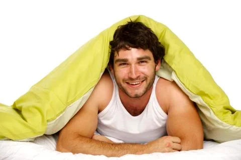 Man smiling in bed under a green duvet Stock Photos