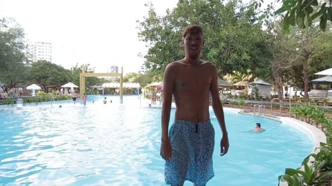 Man smiling to the camera and jumping into the pool Stock Footage 70773914