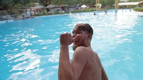 Man smiling to the camera and jumping into the pool Stock Footage 70775233