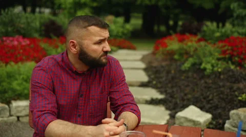 Man is smiling to the camera, sitting at the park Stock Footage 65817985