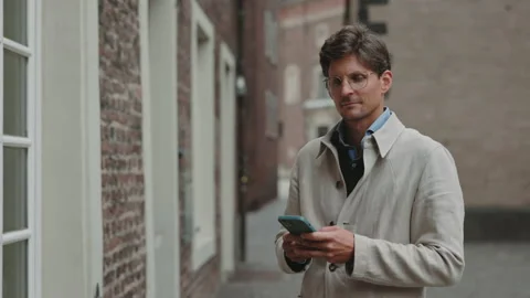 Man smiling on camera while using smartphone on street Stock Footage 167939440