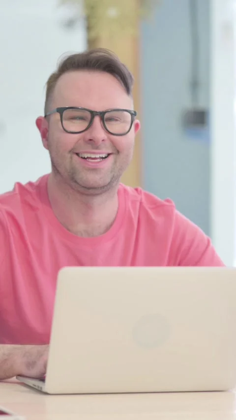 Man Smiling at Camera while using Laptop, vertical video Stock Footage 329105699